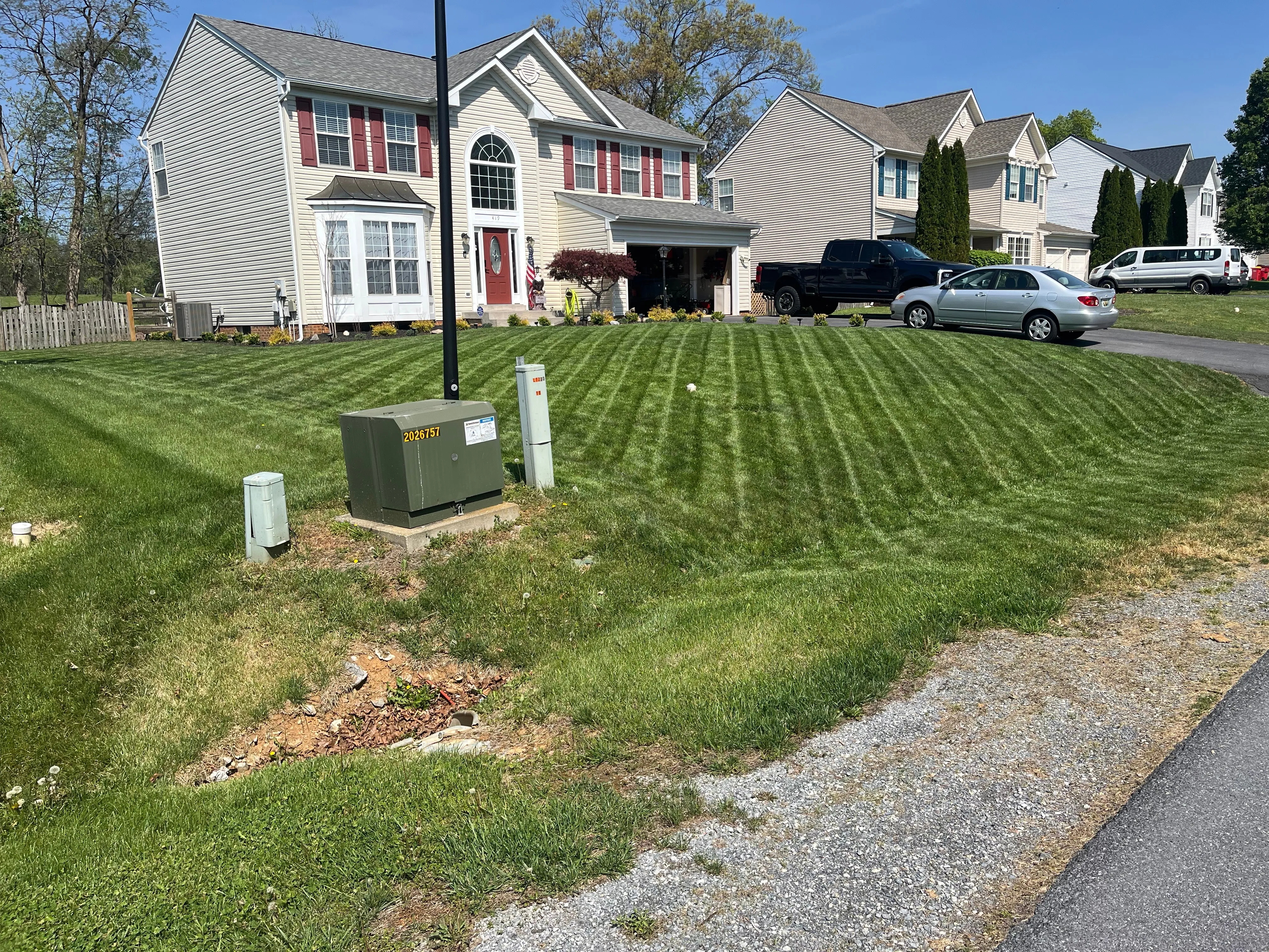 A front lawn freshly mowed into clean, even stripes in a residential neighborhood.